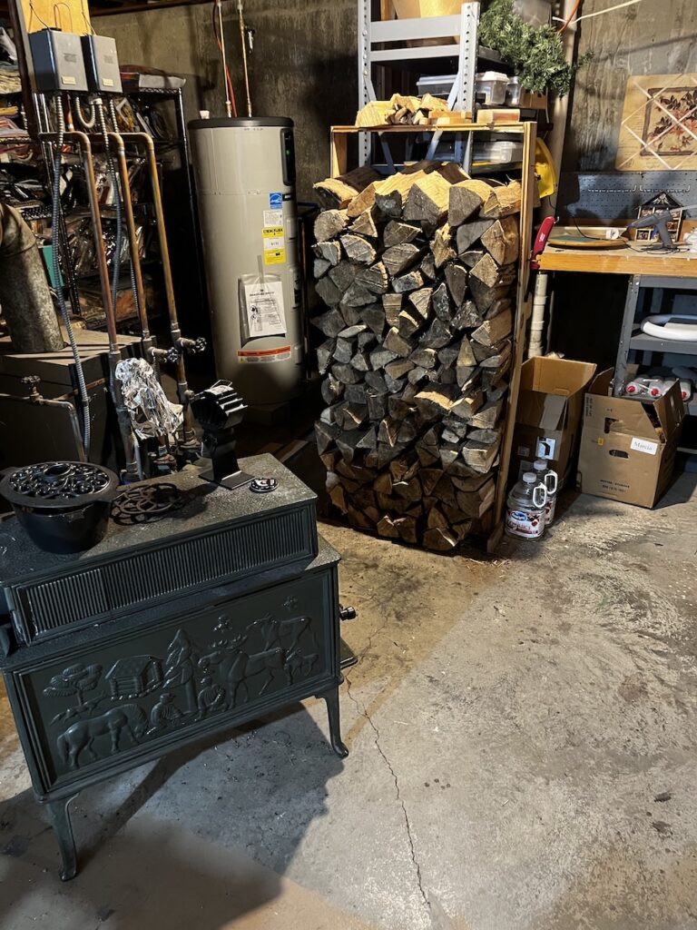 Split hardwood firewood, stocked in the background, the Jotul stove in the foreground in our basement.